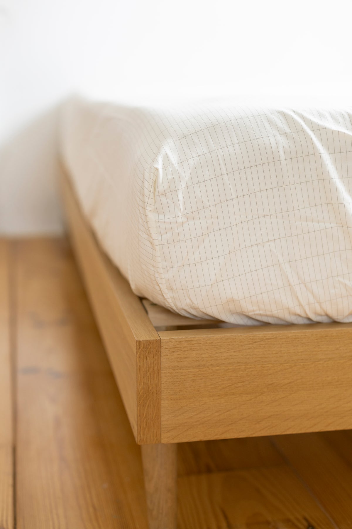 Hoek van het Earthle aardingshoeslaken om het matras op een houten bed, 200 x 160 x 30 cm