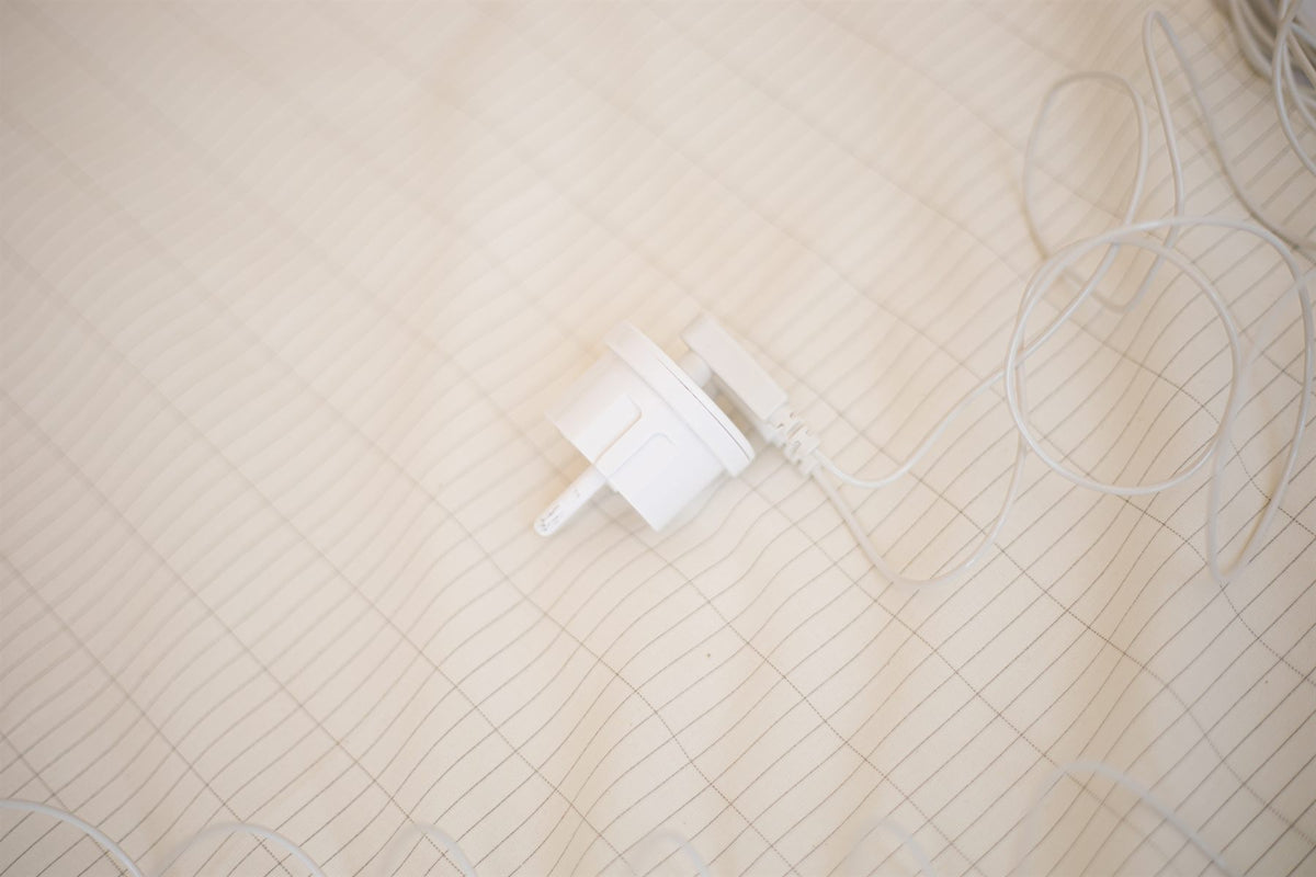 Aardingsstekker met kabel op een Earthle aardingslaken, waarin het geweven zilverraster zichtbaar is