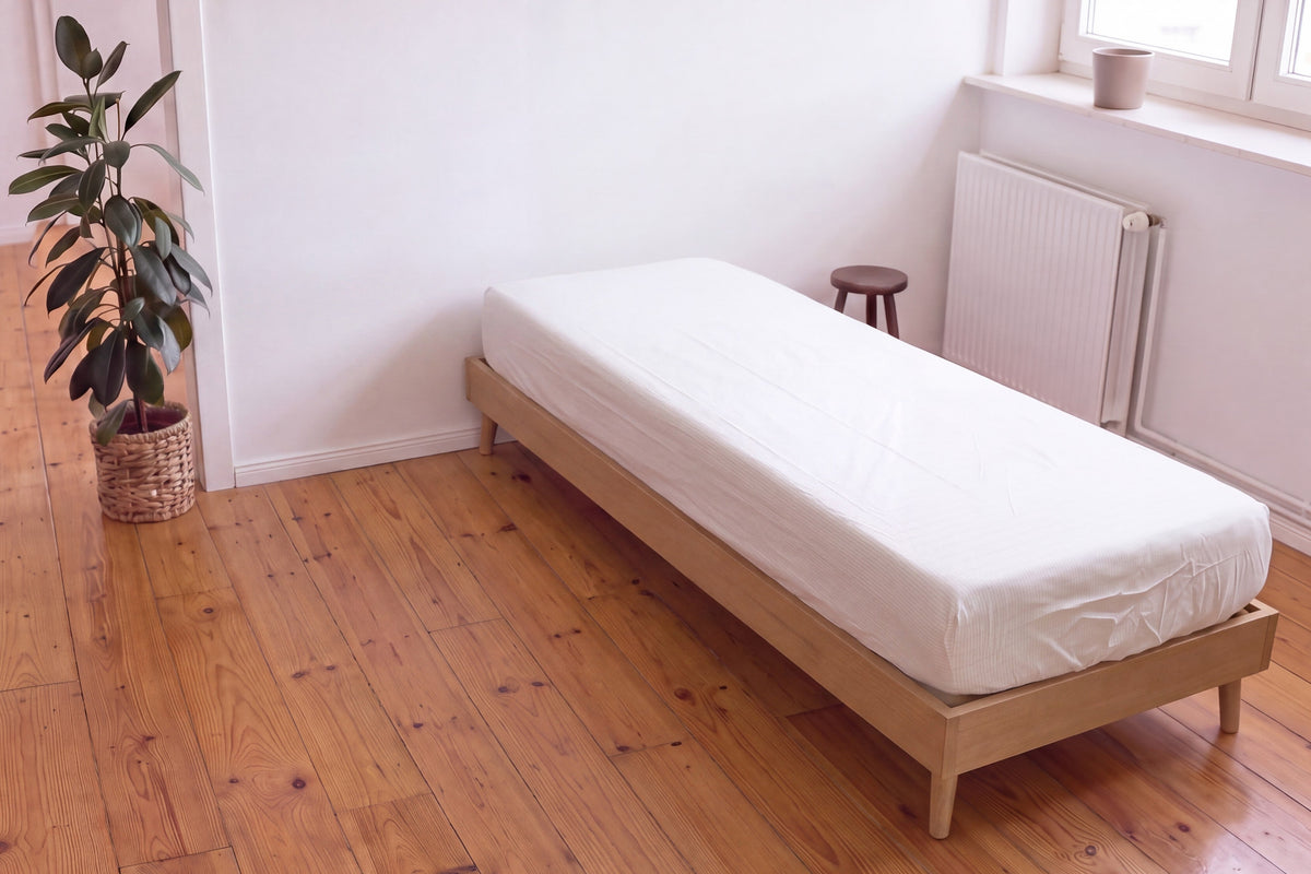 Earthle aardingshoeslaken op een eenpersoonsbed op een houten vloer