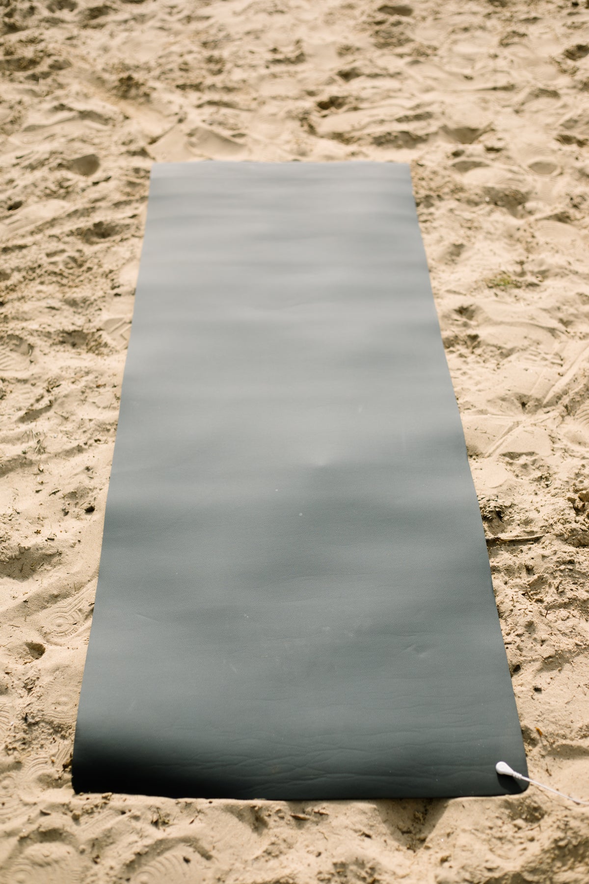 Earthle aardingsyogamat uitgerold in het zand