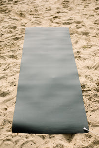 Earthle aardingsyogamat uitgerold in het zand