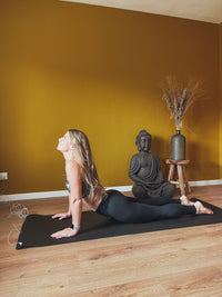 Vrouw die zich uitstrekt op de Earthle aardingsyogamat op een houten vloer