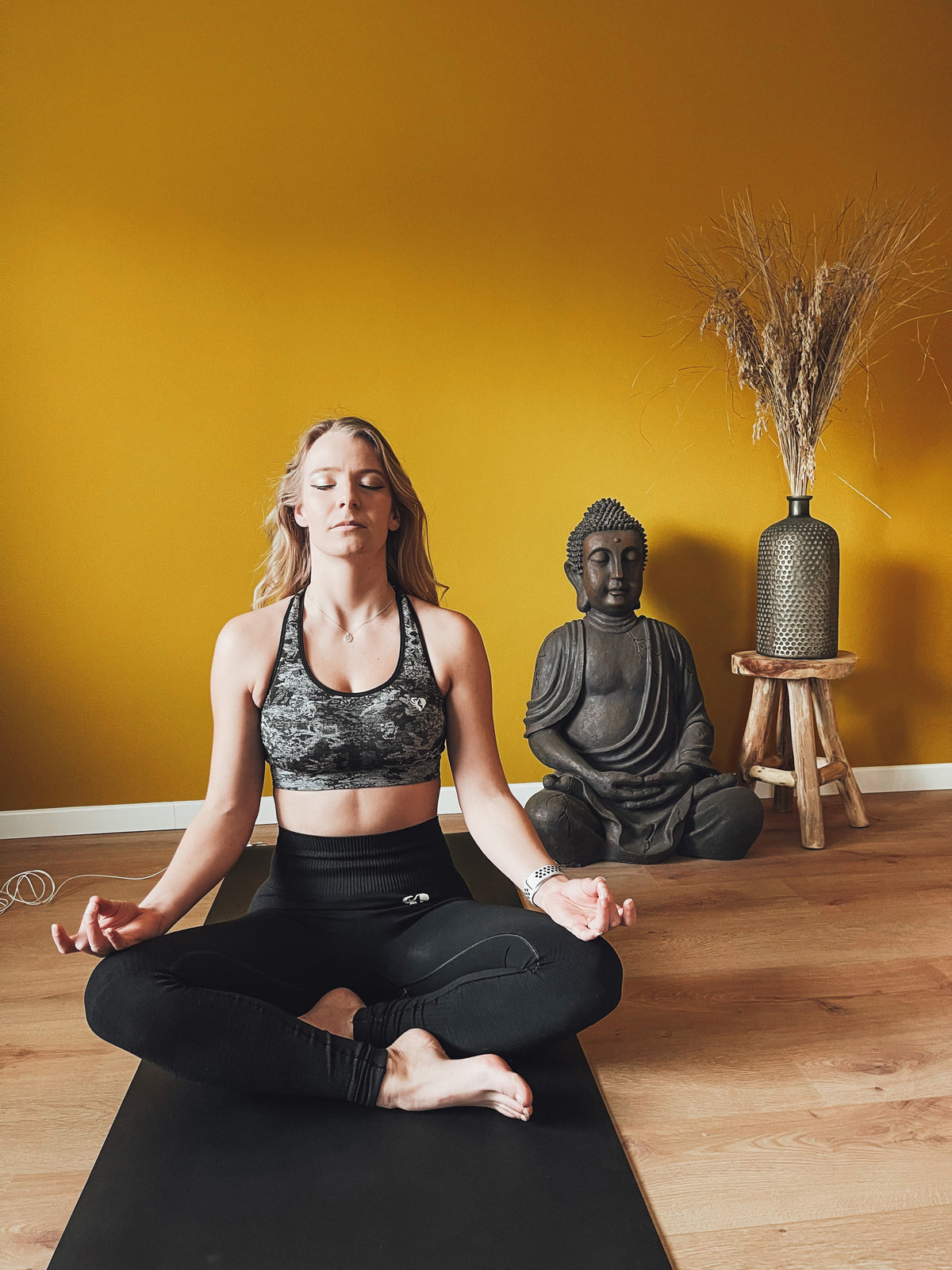 Vrouw in kleermakerszit mediterend op de Earthle aardingsyogamat