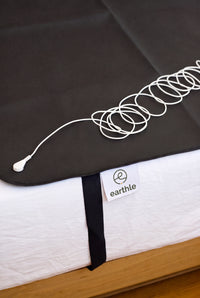 Earthle aardingsslaapmat met de opgerolde aardingskabel erop, 185 x 137 cm