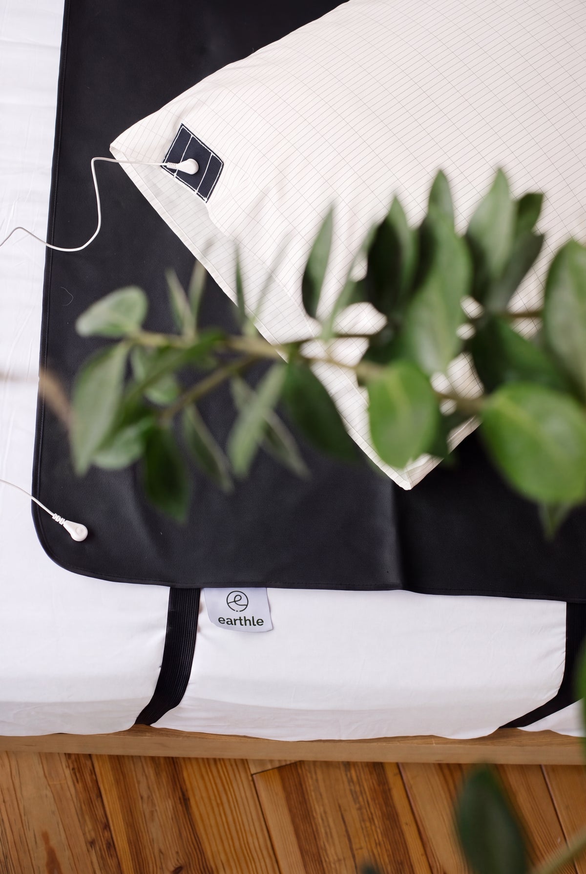 Earthle aardingsslaapmat op bed met kussensloop en kamerplant, 185 x 68 cm